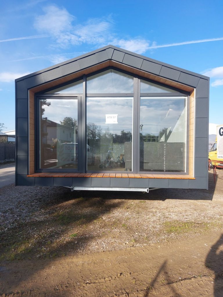 Frontale Giebelfront des Modulhauses ATB 57 mit dreiteiliger Panoramaverglasung und Holzsitzbank.