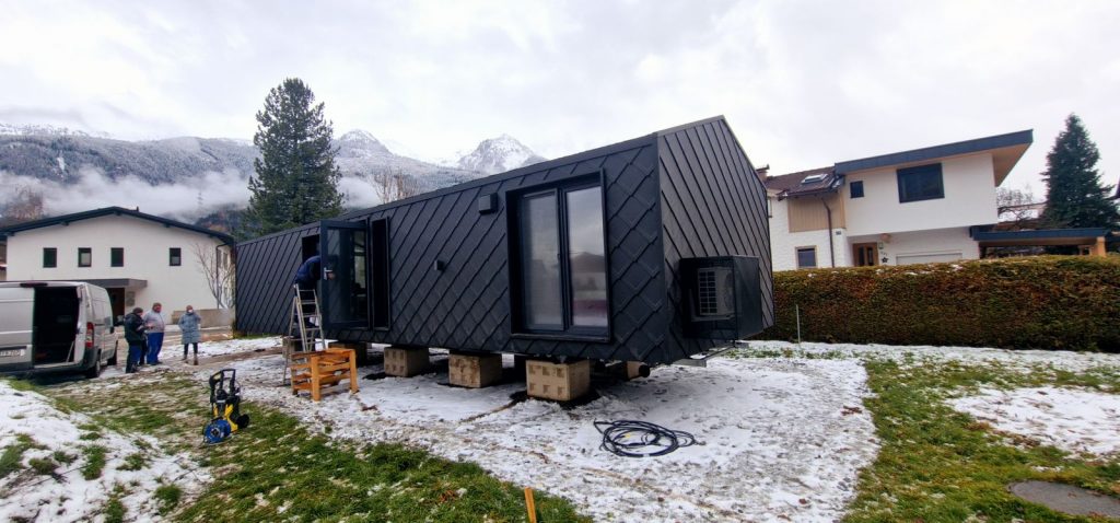 Das schlüsselfertige Modulhaus ATB 60 mit großen Fenstern und Rautenfassade während der Montage vor Alpenpanorama.