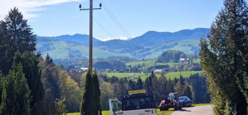 Voralpine Hügellandschaft mit grünen Wiesen und Bergen entlang der Transportroute des Fertighauses