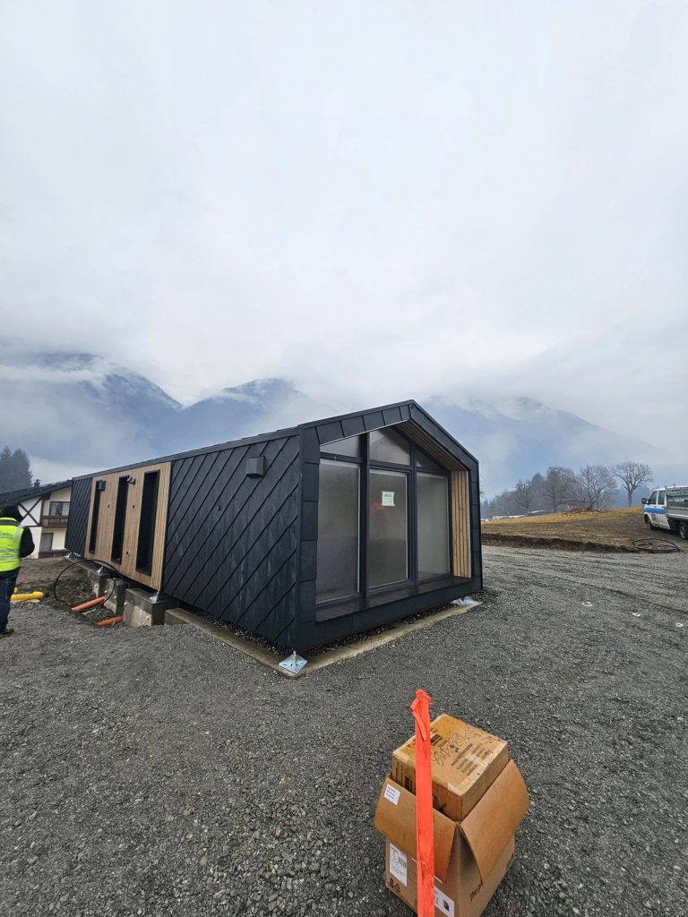 Schlüsselfertiges Modulhaus ATB 70 mit Glasfront und holzverkleideter Seite an einem Wintertag.