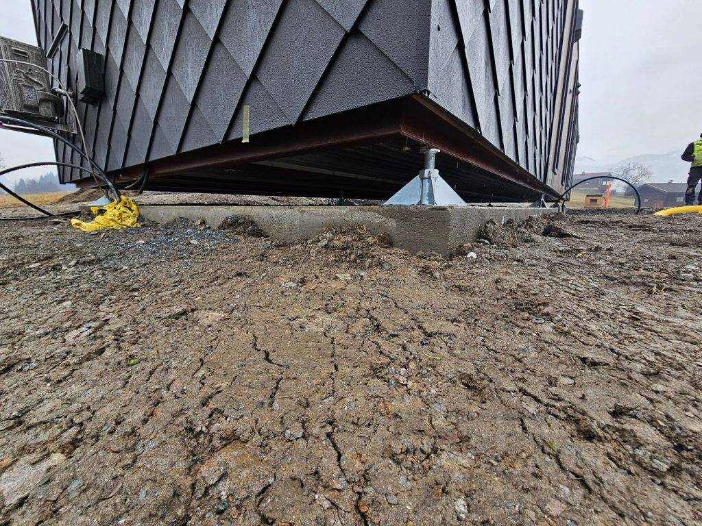Höhenverstellbare Stahlfundamente heben das Ganzjahreshaus-Modul über das Streifenfundament.