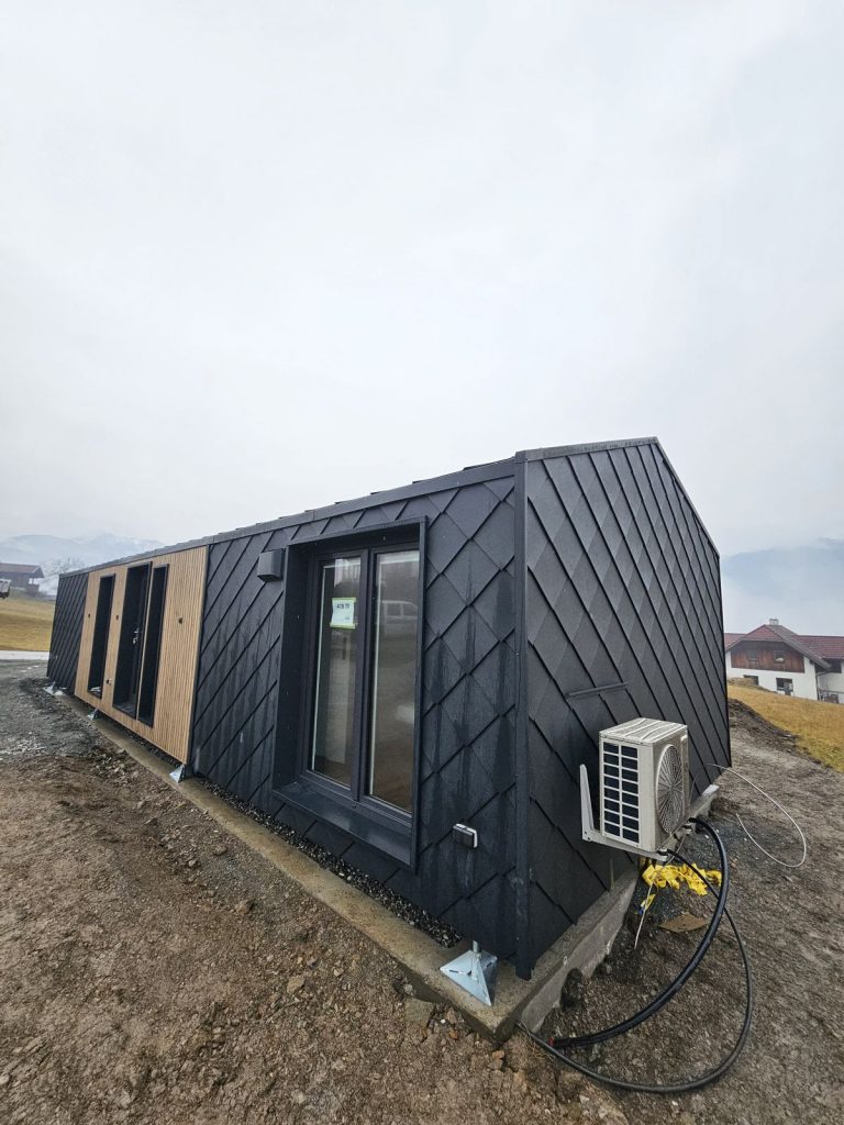 Längsseite des ATB 70 mit Fenster, Holzverkleidung und außenliegender Wärmepumpe.