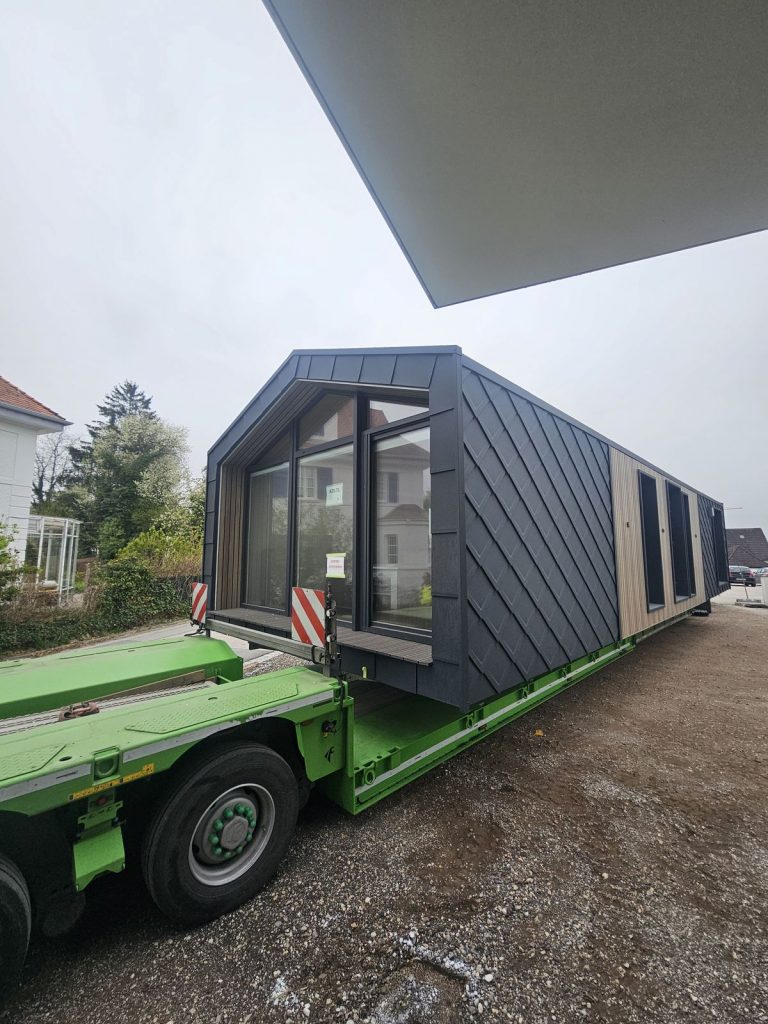 Seitliche Ansicht des ATB 71 mit verglaster Giebelfront und Holzlattung, geliefert als vollständiges Fertigteilhaus.