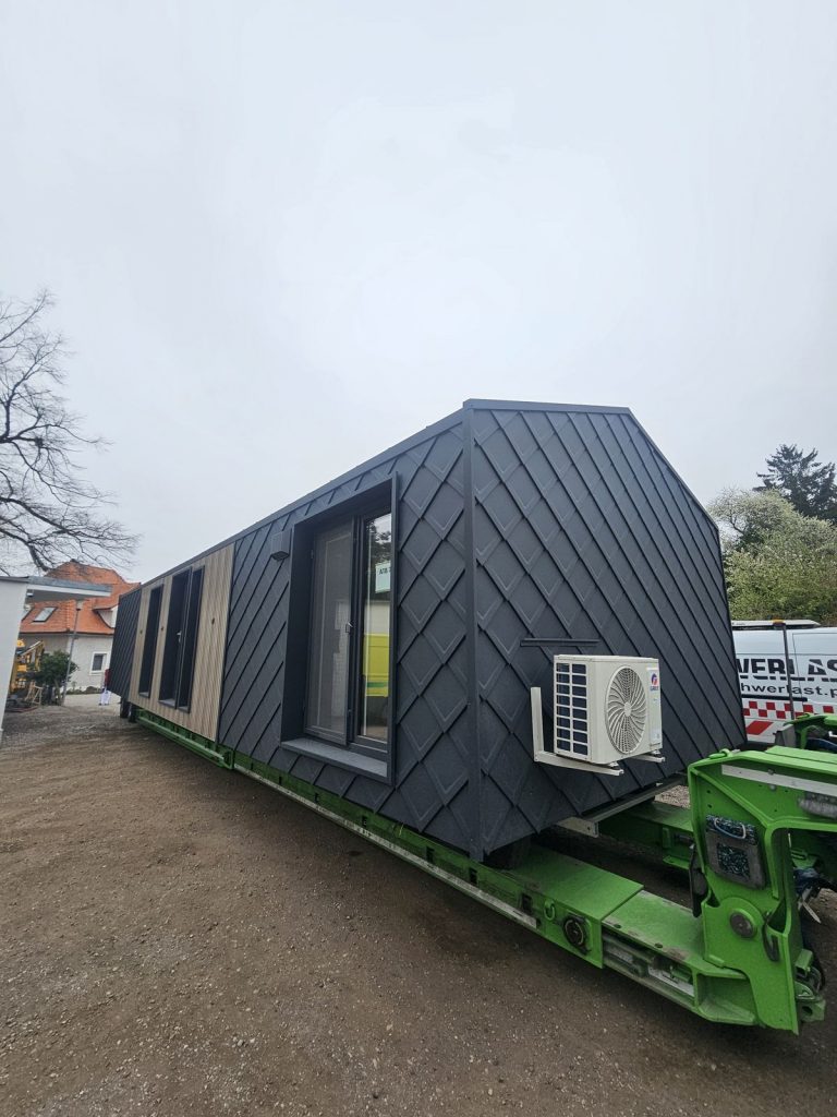 Rückseite des ATB 71 mit anthraziter Rautenschindel-Fassade, bodentiefem Fenster und außenliegender Klimaeinheit.