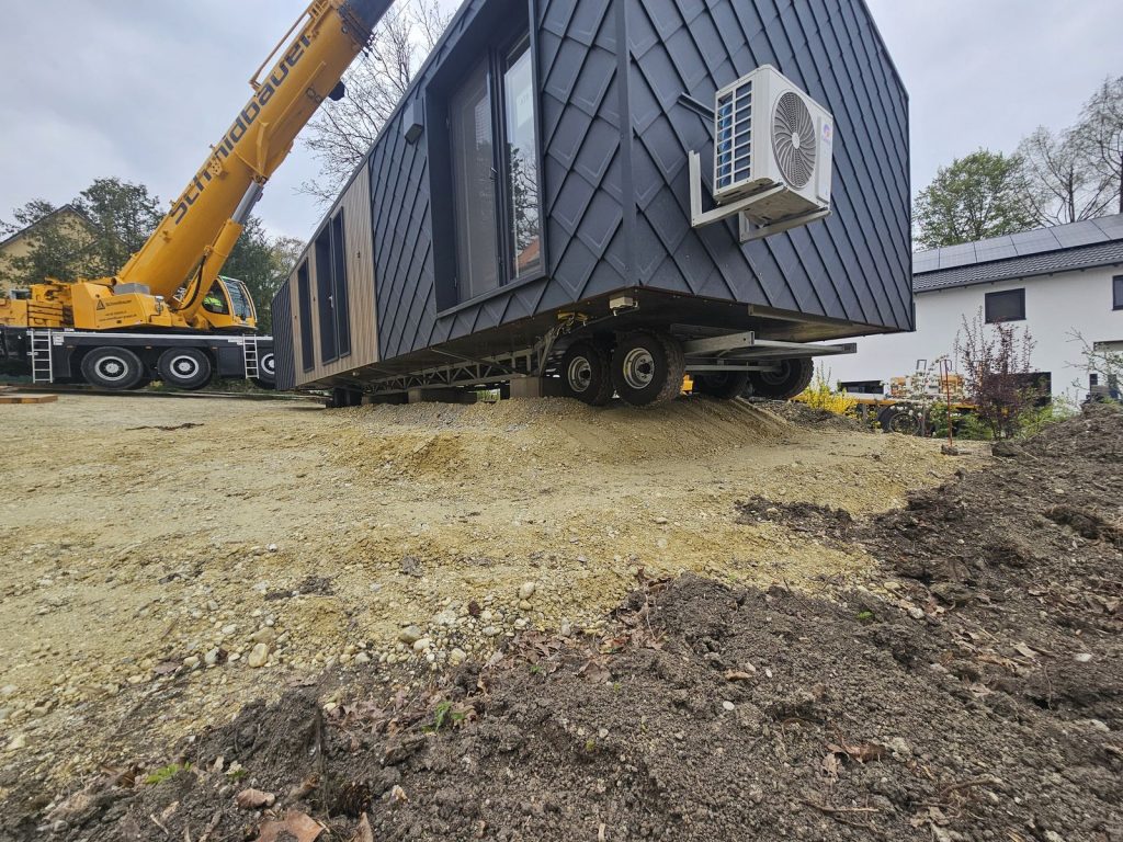 ATB 71 kurz vor dem Absetzen, Untersicht auf Rautenfassade und Fahrwerk mit Kran im Hintergrund.