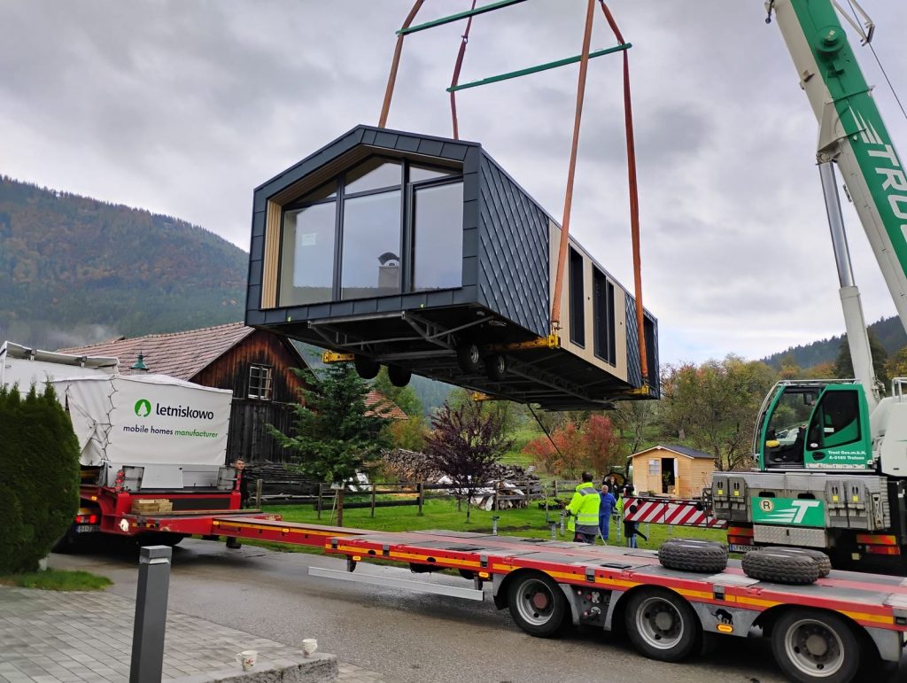 Premium-Modulhaus mit Panoramagiebel wird vom Kran zum vorbereiteten Aufstellplatz gehoben.
