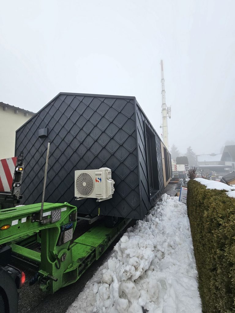 Nahaufnahme der anthrazitgrauen Rautenfassade des Modulhauses ATB 76 mit Außenklimagerät auf dem Tieflader.