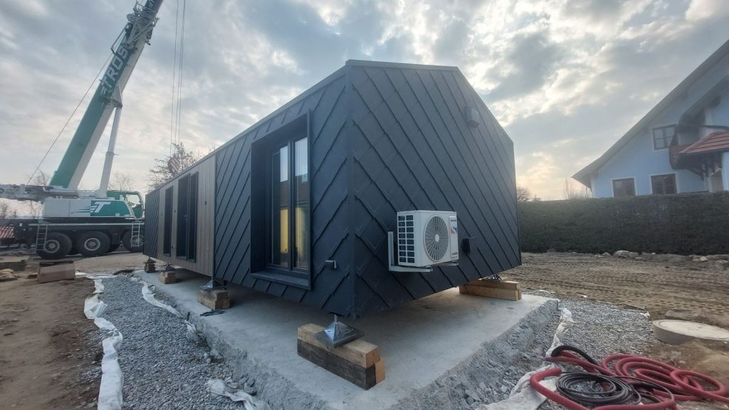 ATB 77 mit Rautenfassade und Wärmepumpe im Abendlicht, Kran und Wohnhaus im Hintergrund