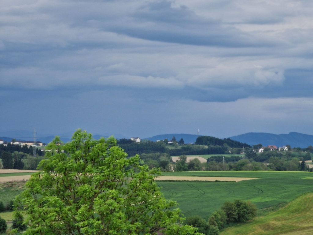 Weite Hügellandschaft mit grünen Feldern und bewölktem Himmel im Umland eines BOND Modulhauses