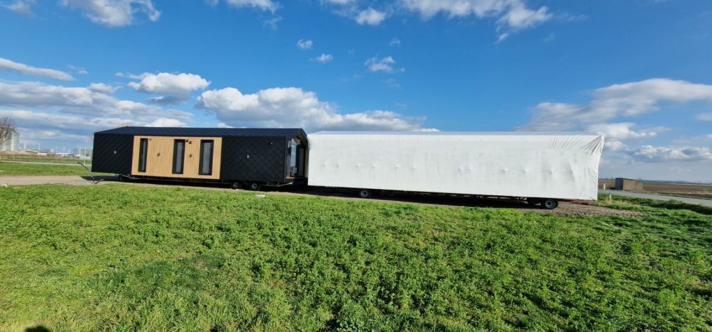 Seitenansicht des ATB 41 mit Holzlattung und Rautenschindeln neben einem transportfertig folierten Modul in Raasdorf.