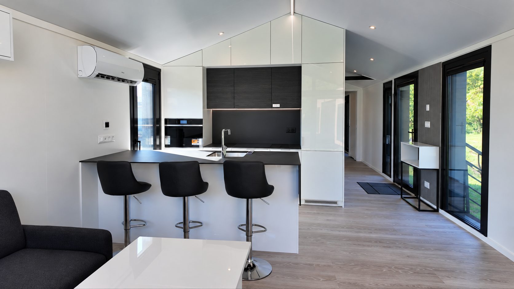 Kücheninsel mit Arbeitsplatte NERO LUNA und drei schwarzen Barhockern im Modulhaus Diamond +Plus ATB-38.