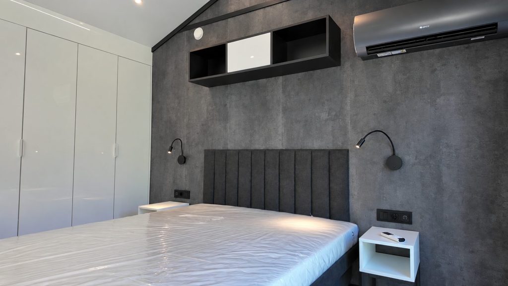 Schlafzimmer im Modulhaus Diamond +Plus ATB-38 mit Doppelbett 160 × 200 und dunkler Wandfläche FIBO LENTINI DARK.