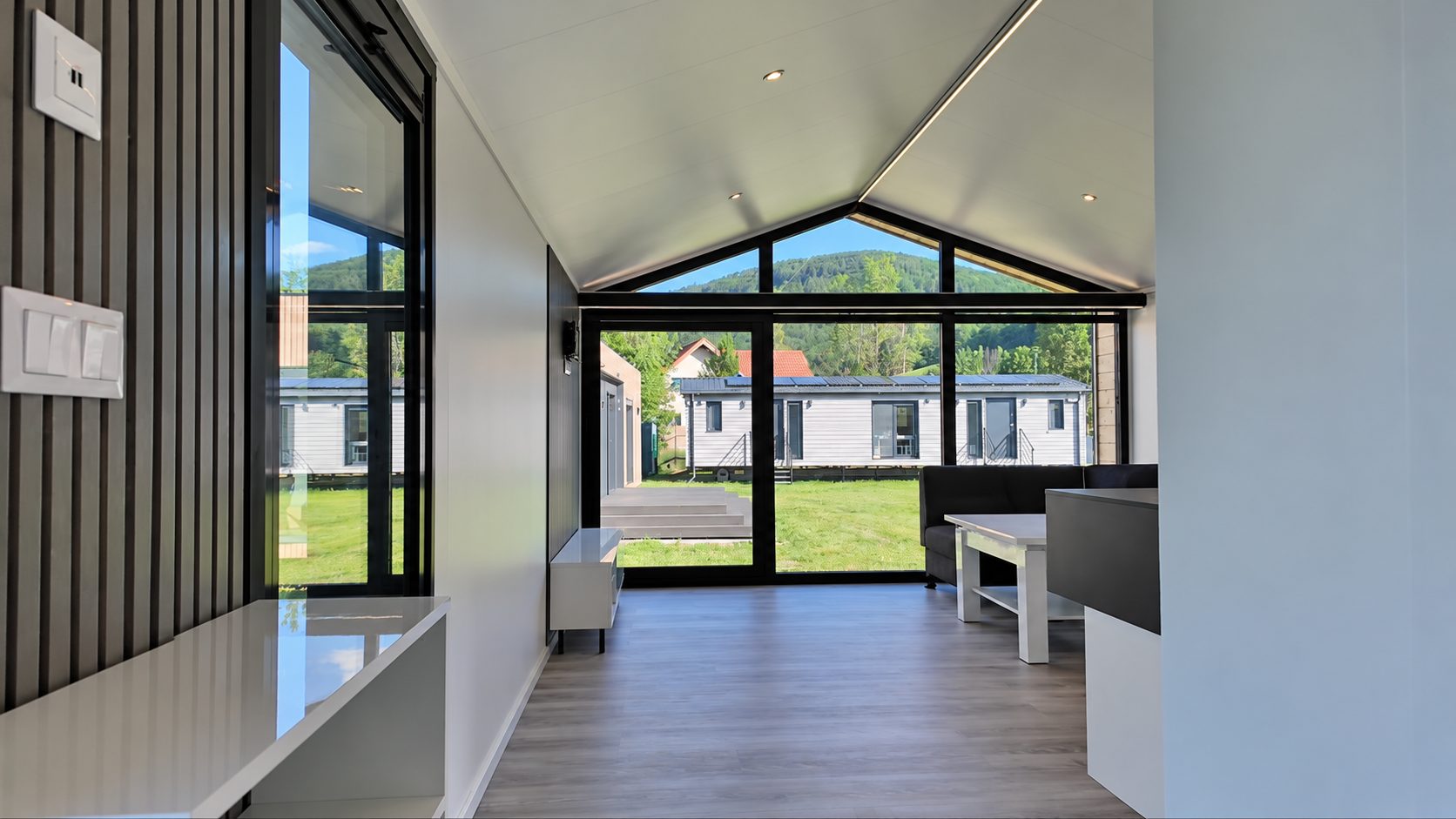 Wohnbereich im Modulhaus Diamond +Plus ATB-38 mit Blick auf die bodentief verglaste Giebelwand.