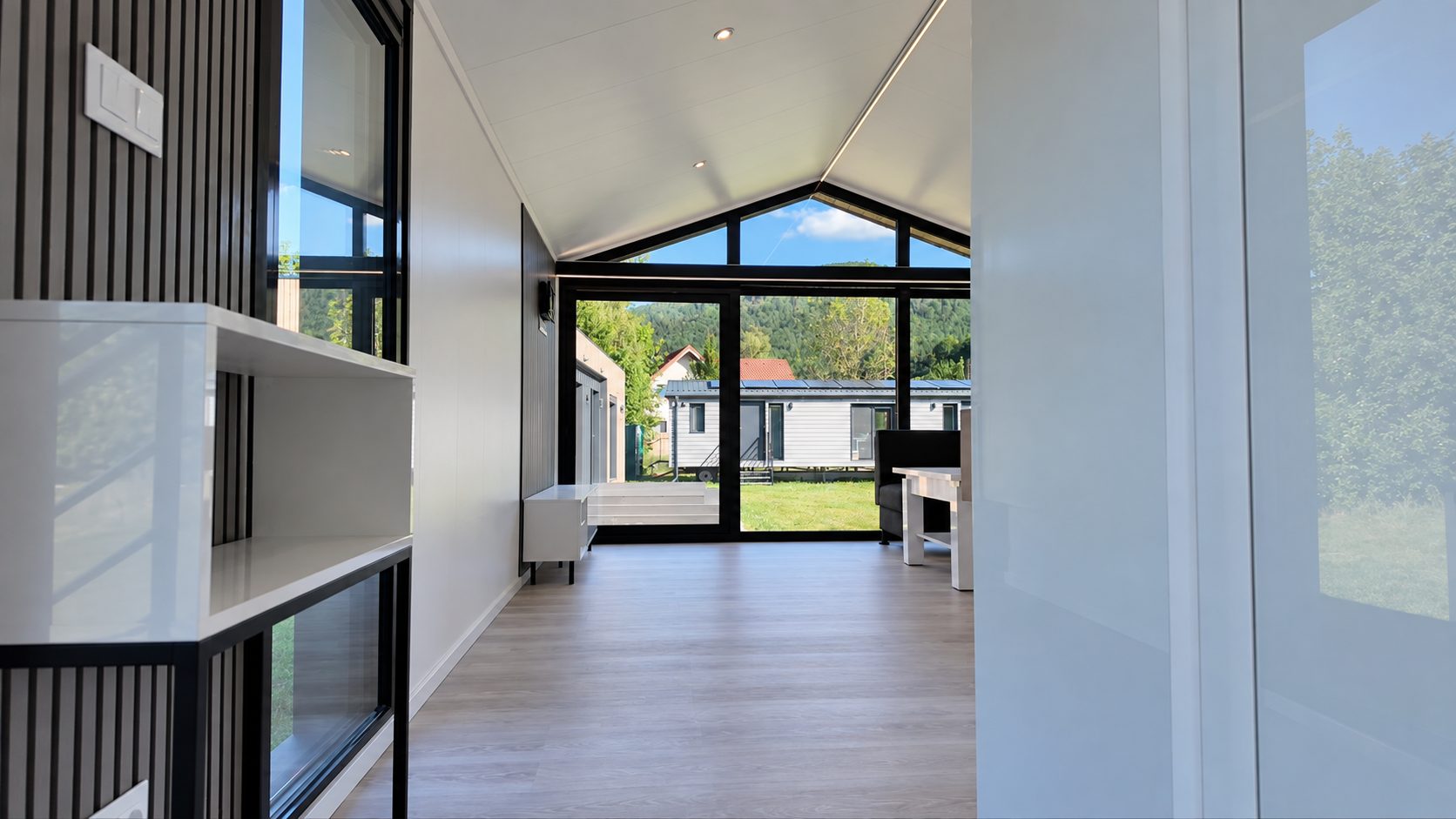 Wohnbereich des Diamond +Plus ATB-38 mit Regal, Sitzgruppe und bodentiefer Verglasung.
