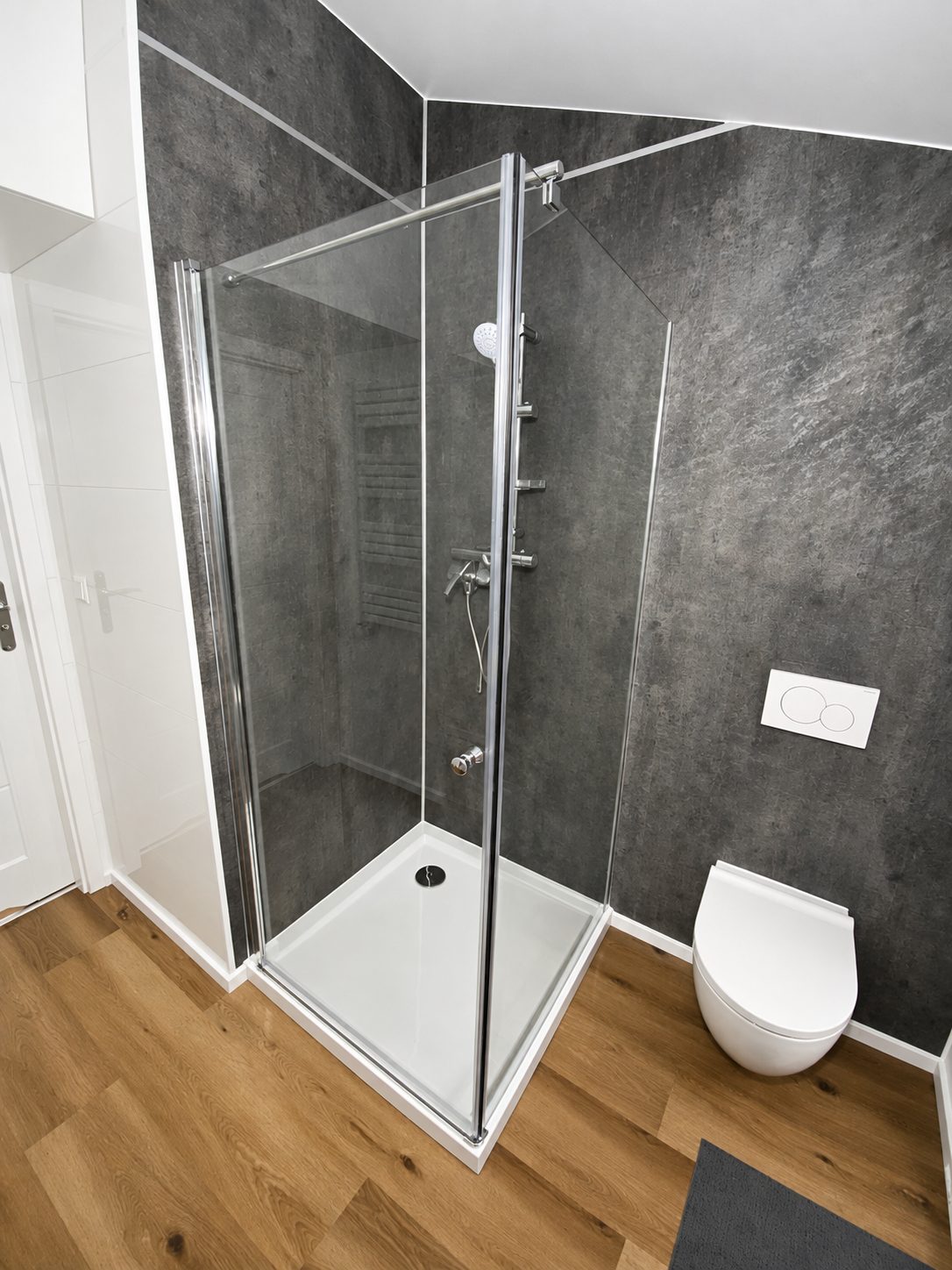 Bad im Modulhaus Diamond +Plus Deluxe ATB-62 mit Glasdusche, dunkler Wandverkleidung und wandhängendem WC.