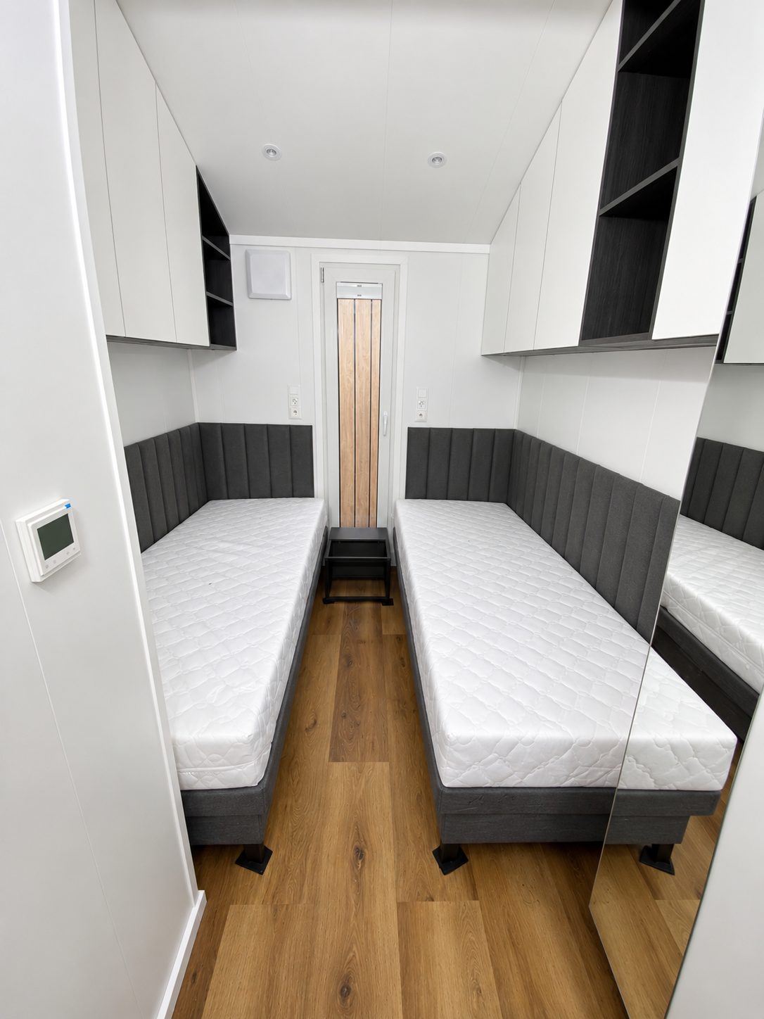 Gästezimmer im Modulhaus Diamond +Plus Deluxe ATB-62 mit gepolsterten Wandpaneelen und Einbauschränken.