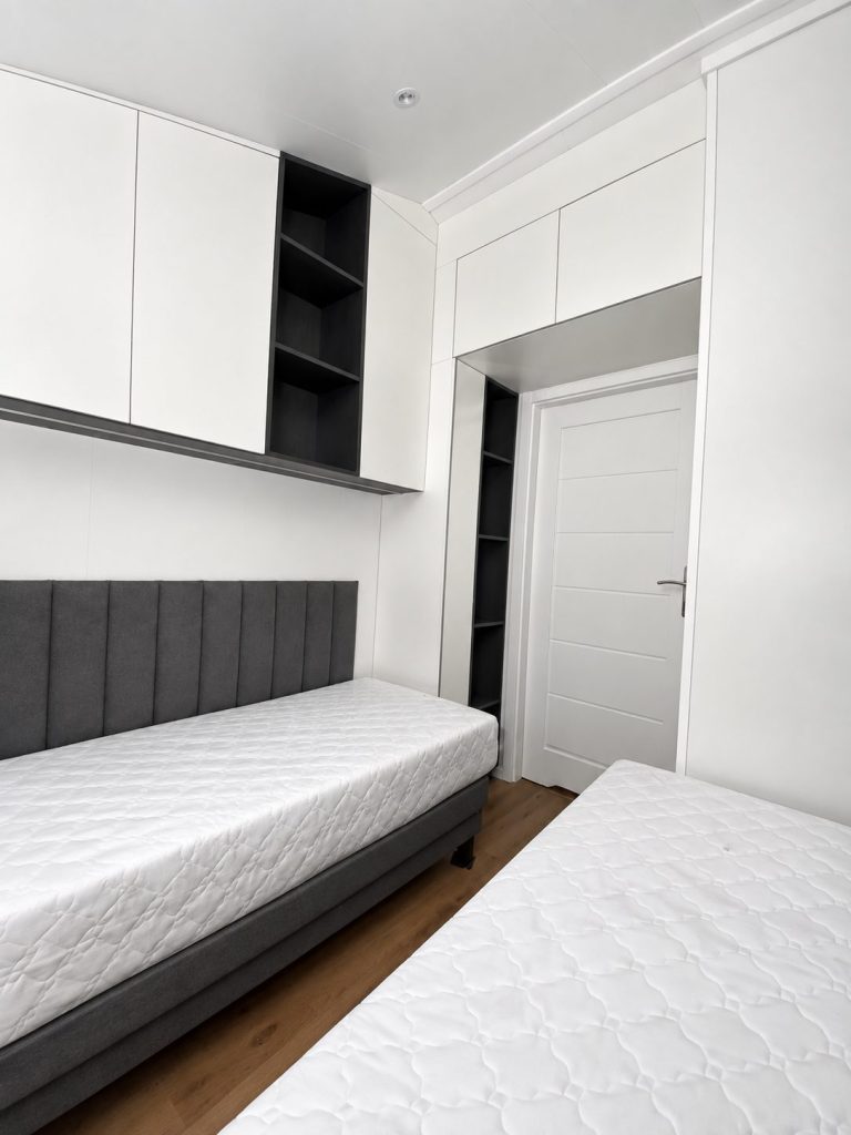 Gästezimmer des Diamond +Plus Deluxe ATB-62 mit Wandpaneelen, Oberschränken und Tür zum Flur.