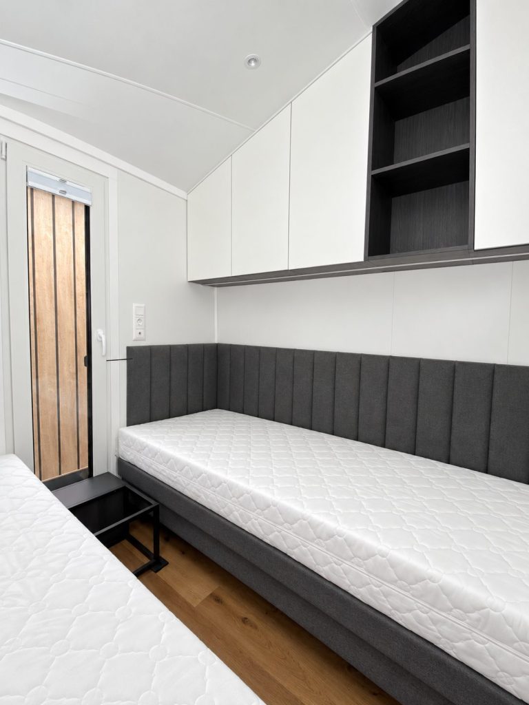 Gästezimmer des Diamond +Plus Deluxe ATB-62 mit offenem Regal und schmalem Fenster.