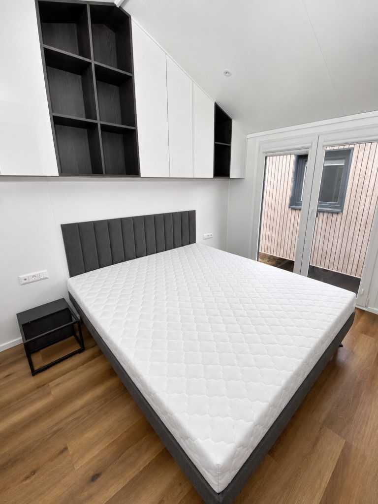 Doppelbett mit gepolstertem Kopfteil und Fenstertür im Schlafzimmer des Diamond +Plus Deluxe ATB-62.